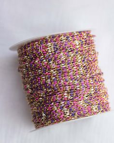 a spool of pink and gold thread on a white surface