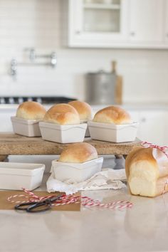 bread rolls sitting on top of a cutting board next to bowls and utensils