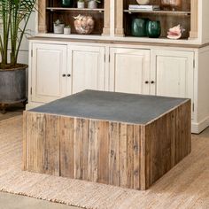 a wooden table sitting in front of a hutch filled with vases and plants