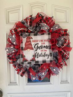 a red and black christmas wreath with the words gnome on it hanging from a white door