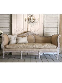 a couch sitting on top of a wooden floor next to a chandelier