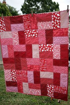 a red and white quilt hanging from a clothes line