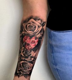 a woman's arm with roses on it and a red diamond in the middle