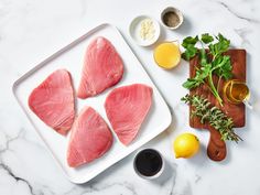 raw fish fillets on a cutting board with lemons, parsley and olive oil