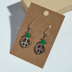 Handmade peace sign drop earrings with translucent green bead detail! These lightweight earrings are a perfect gift or addition to your jewelry collection. Made with silver-colored peace signs, green-colored beads, and Nickel-free earring hooks. Enjoy! Peace Sign Jewelry, Peace Signs, Nickel Free Earrings, Lightweight Earrings, Earring Hooks, Light Weight Earrings, Green Bead, Peace Sign, Hippie Boho