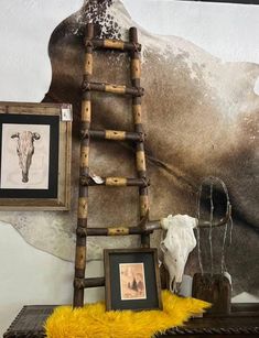 an old ladder leaning against a wall next to a cow skull and other items on a table