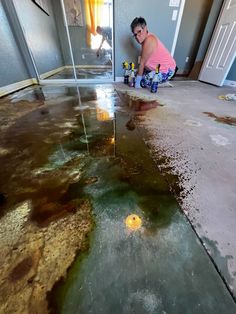 a man kneeling down on the floor in front of a flooded room with water coming from it