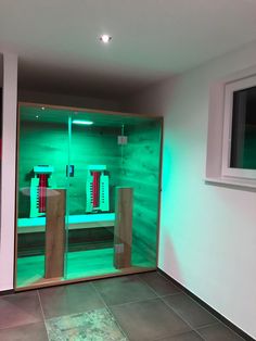 a room that has some green lights on the wall and two wooden benches in front of it