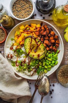 a white plate topped with rice and vegetables next to bowls of beans, avocado