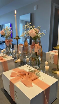 the table is set with candles and flowers in vases, wrapped presents on them