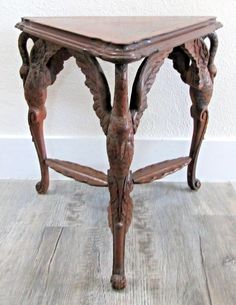 an old wooden table with carved designs on it's legs and bottom part, sitting on a wood floor