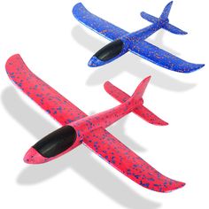 two toy airplanes flying next to each other on a white surface with blue and red speckles