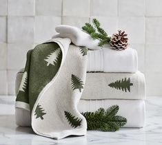 a stack of folded towels with pine cones on top and evergreen leaves on the bottom