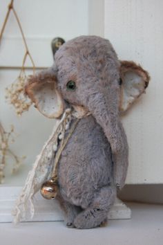 an elephant is sitting on a shelf next to some flowers and a doorknob