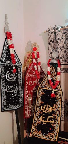 three decorated items are on display in a room with white walls and black and red decor