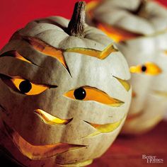 two carved pumpkins sitting on top of a wooden table with eyes painted on them