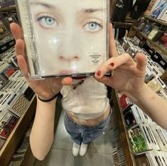 a woman holding up a cd in front of her face with the cover pulled back