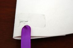 a piece of paper with a purple ribbon attached to it