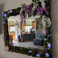 a mirror that has flowers on it in the middle of a room with a couch