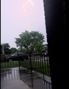 a lightning bolt is seen in the sky over a fence