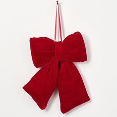 a red bow ornament hanging on a white wall