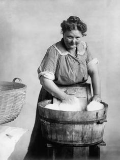 an old photo of a woman washing her hands in a bucket with soap on it