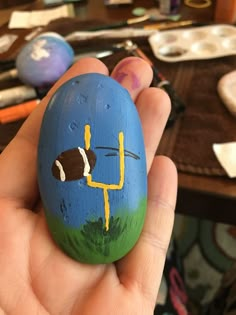 a hand holding a painted rock with a cartoon character on it