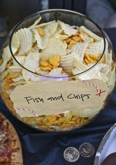 a glass bowl filled with fish and chips next to a pizza