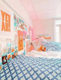 a bed with blue and white bedspread next to a wall covered in pictures