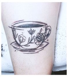 a black and white photo of a coffee cup with flowers on it's side