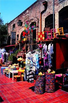 an outdoor market with clothes and other items