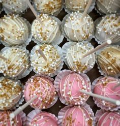 there are many pink and white desserts on the table with gold sprinkles