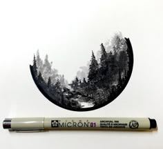 a pen is sitting next to a drawing of trees in a circle with the word micronit on it