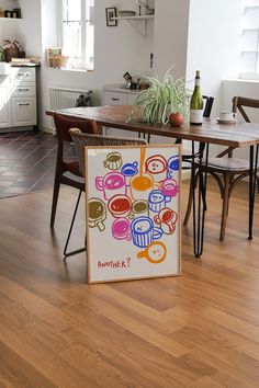 a table and chairs in a room with wood flooring next to a painting on the wall