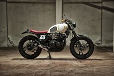 a white and red motorcycle parked in front of a building with concrete walls behind it