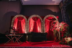 a stage set up with red drapes and lights on the walls, couches and tables