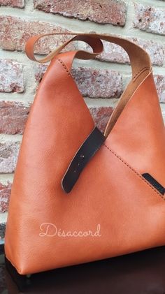 a brown leather purse sitting on top of a wooden table next to a brick wall