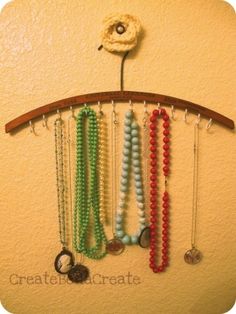 a wooden rack with beads and necklaces hanging from it's side on a wall