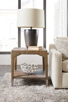 a living room with a couch, table and lamp on it in front of a large window