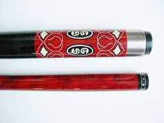 two red and black pool cues laying next to each other on a white surface