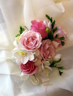 a bridal bouquet with pink roses and white lilies on a satin fabric background