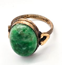 a green stone ring sitting on top of a white surface