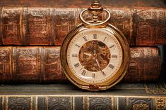 an antique pocket watch sitting on top of some books with the time being 11 00