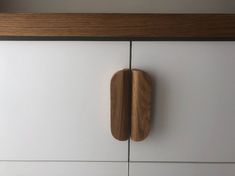 a close up of a wooden door handle on a white and wood cabinet with drawers