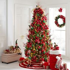 a christmas tree decorated with red, green and gold ornaments in a living room area