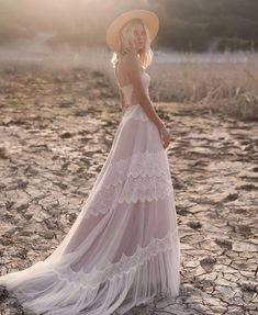 a woman in a white dress and hat standing on the ground wearing a straw hat