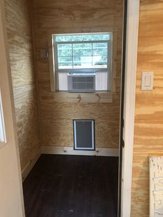 an empty room with wood paneling and a window