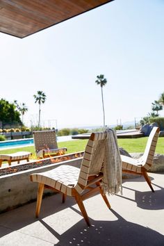 two lawn chairs sitting on top of a patio next to a swimming pool