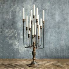 a tall metal candle holder with eight candles in it's center on a wooden table