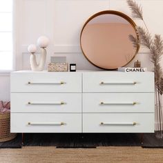 a white dresser topped with a round mirror